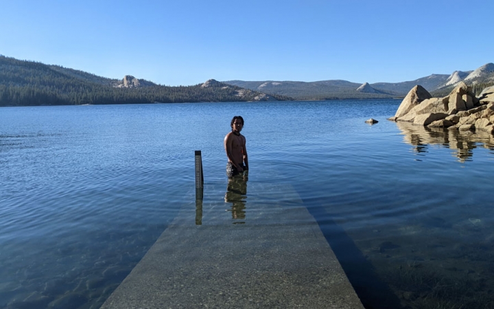 a person stands in waist deep blue water on a backpacking trip for bipoc 